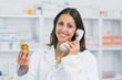 Female pharmacist holding a bottle of pills while phoning