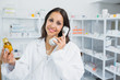 Pharmacist holding a bottle of pills while phoning