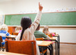 Back view of schoolgirl raising her hand