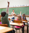 Back view of young pupils raising hands