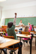 Back view of primary school students raising hands