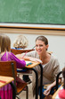 Smiling teacher kneeling next to students desk
