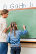 Photo : Teacher and student writing on blackboard together Teacher and student writing on blackboard together