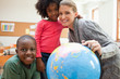 Smiling teacher with her students next to globe