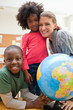 Smiling students with teacher next to globe