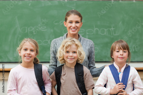 Photo: Teacher with her students standing in front of black board Teacher with her students standing in front of black board