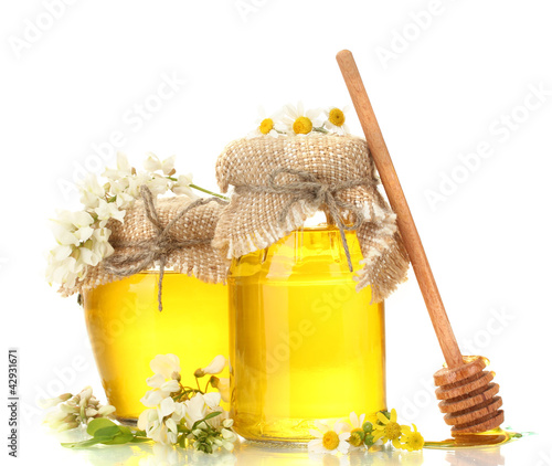 Photo: Sweet honey in jars and acacia flowers isolated on white Sweet honey in jars and acacia flowers isolated on white