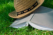 Book and straw hat on grass