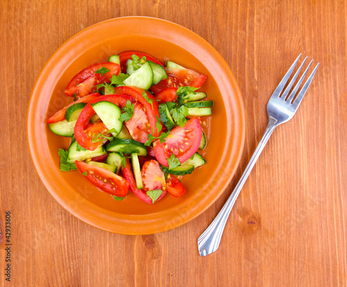 Foto: Fresh salad with tomatoes and cucumbers on wooden background Fresh salad with tomatoes and cucumbers on wooden background