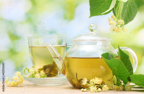 Photo: teapot and cup with linden tea and flowers teapot and cup with linden tea and flowers