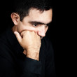 Hispanic man thinking with a fist on his chin isolated on black