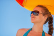 Photo: Happy woman in sunglasses on windy beach looking on copy space Happy woman in sunglasses on windy beach looking on copy space