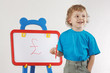 Little smiling blond boy drew a pound sign on the whiteboard