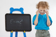 Little amazed boy with glasses shows Einstein's formula