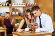 Paar schaut auf Tablet Computer im Café