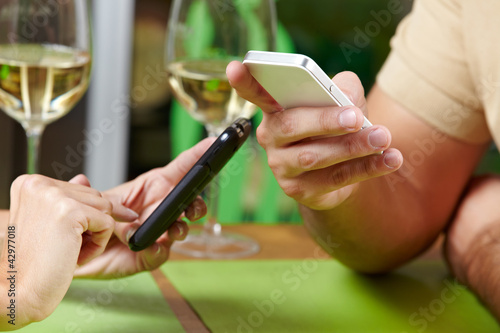 Photo: Paar mit Smartphones im Restaurant Paar mit Smartphones im Restaurant