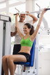 Personal trainer helping woman training in wellness club