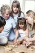An old woman sitting on the floor playing Jenga with her grandchildren