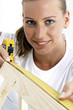 A woman using a measuring tape to measure a wood