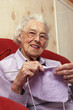 An old bespectacled lady sitting on the couch knitting