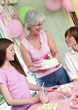 A woman bringing out a birthday cake for her daughter