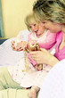 A woman playing doll with her young daughter