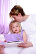 A woman sitting on the bed kissing her daughter's head