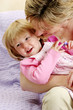 Photo: A woman trying to kiss her daughter who is sitting on her lap A woman trying to kiss her daughter who is sitting on her lap