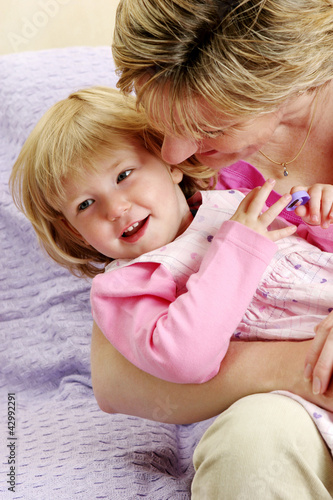 Photo: A woman trying to kiss her daughter who is sitting on her lap A woman trying to kiss her daughter who is sitting on her lap