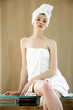 Foto: A woman with her hair and body wrapped up in towel sitting on the table A woman with her hair and body wrapped up in towel sitting on the table