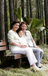 A young boy sitting on the bench with his mother and grandmother 