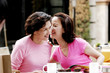 A woman whispering a joke to her mother 