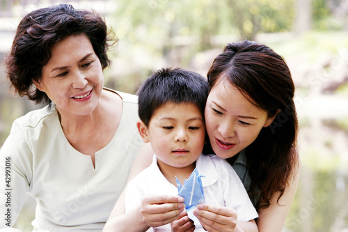 Photo: A woman teaching her son how to fold a paper bird A woman teaching her son how to fold a paper bird