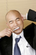 Bald man in business suit brushing his teeth 