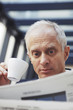 Businessman drinking coffee while reading newspaper