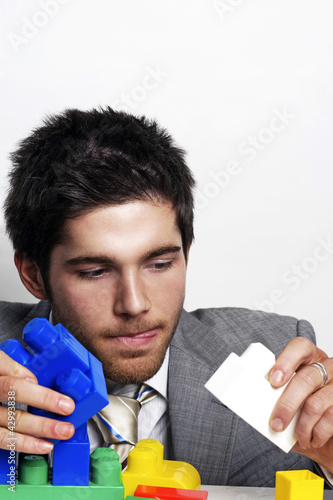 Photo: Businessman playing with colourful plastic bricks Businessman playing with colourful plastic bricks