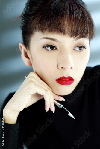 Photo: Businesswoman holding a pen, thinking Businesswoman holding a pen, thinking