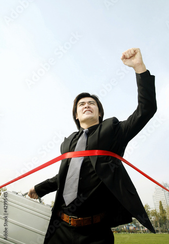 Photo: Businessman with briefcase running to the finishing line Businessman with briefcase running to the finishing line