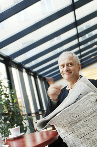 Photo: Businessman calling the waiter while holding a newspaper Businessman calling the waiter while holding a newspaper