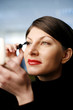 Businesswoman applying mascara