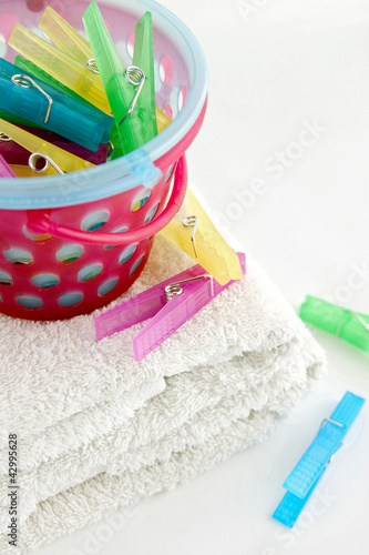 Photo: Colourful plastic clothes pegs in basket Colourful plastic clothes pegs in basket