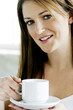 A young lady looking at camera while holding a cup of coffee