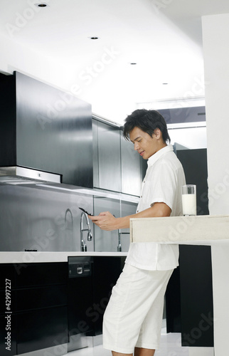 Photo: Man making a phone call in the kitchen Man making a phone call in the kitchen