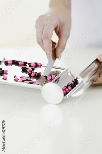 Photo: Doctor counting pills on pharmaceutical tray Doctor counting pills on pharmaceutical tray