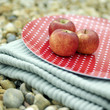 Three red apples on a folded picnic blanket