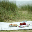 Bakewell tarts, red apples, cup and plastic forks on a picnic blanket
