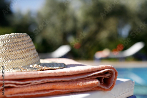 Photo: Close up of hat and towel near poolside Close up of hat and towel near poolside