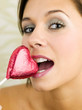 Woman biting a heart-shaped chocolate