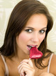 Woman biting a heart-shaped chocolate