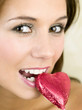 Woman biting a heart-shaped chocolate